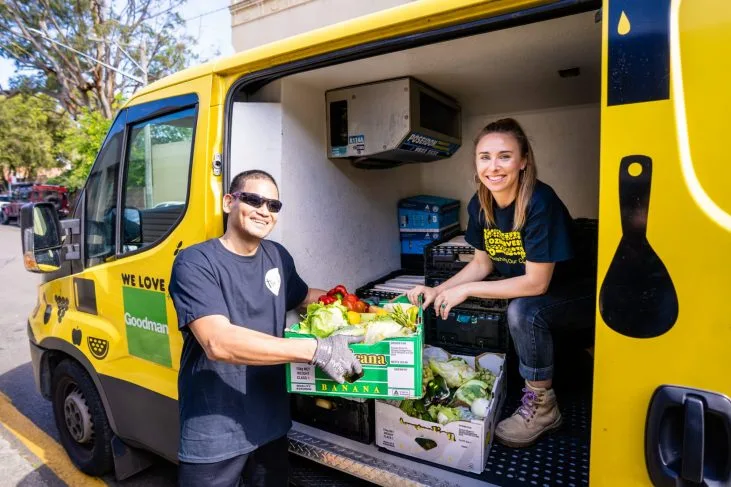 OzHarvest female driver smiling and handing over crates of food to staff member of The Way