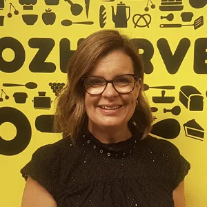 OzHarvest Head of People and Culture Sharon Gray smiling in front of a yellow wall.