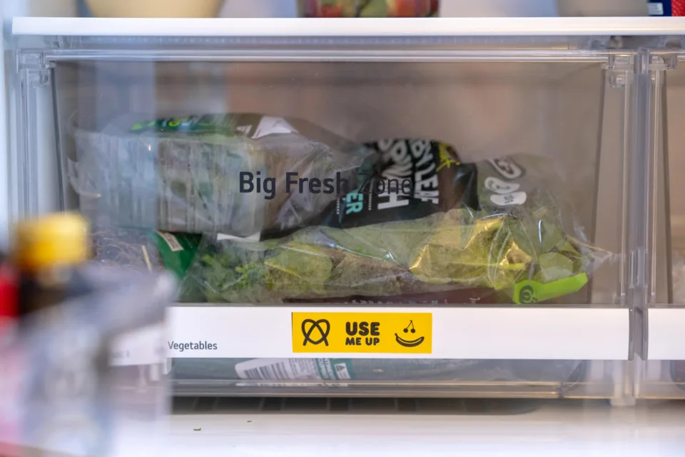 Two bagged salads in a fridge crisper with use it up tape