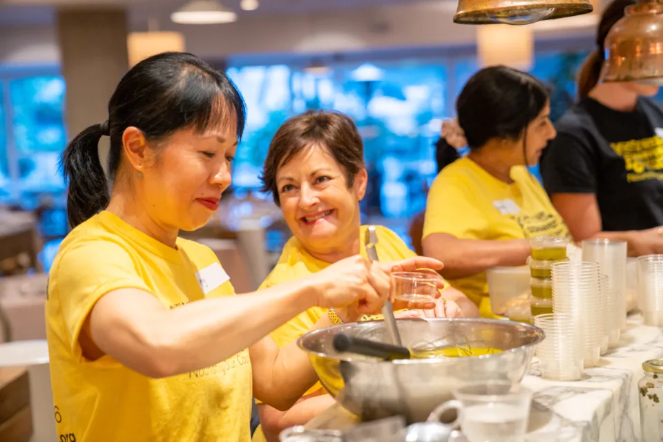 Two volunteers cooking at Rockpool. This image is used for Cooking for a Cause