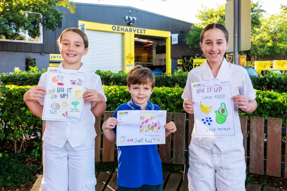 Kids holding up OzHarvest Fight Food Waste competition entries.