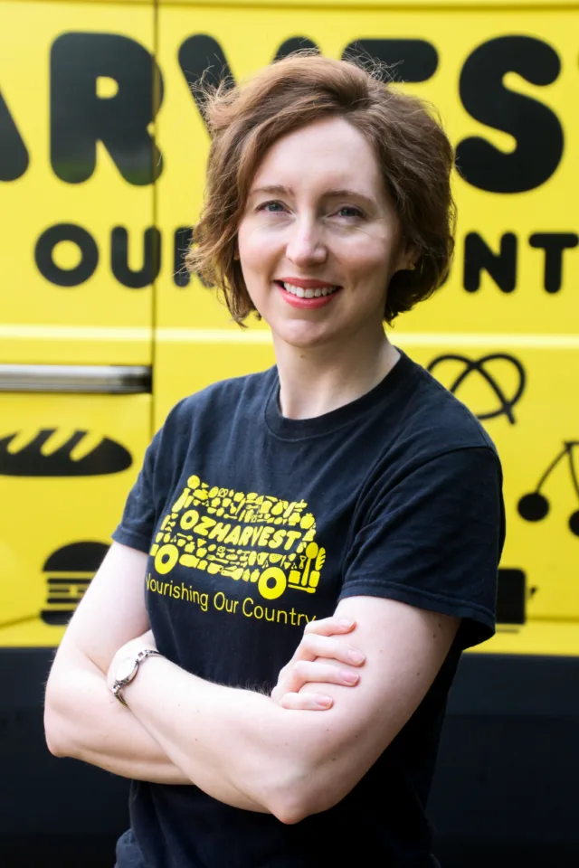 OzHarvest Head of Advocacy, Community and Education Sarah Flomersfeld smiling in front of an OzHarvest van.